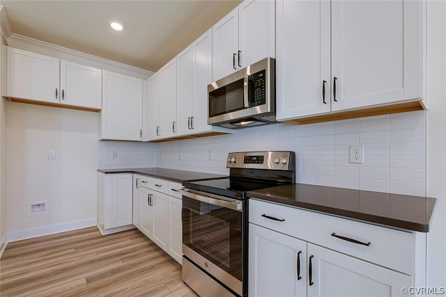 kitchen with stainless steel appliances, white cabinets, light hardwood / wood-style floors, and decorative backsplash