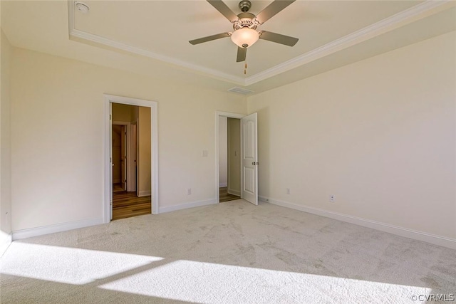 unfurnished bedroom featuring a raised ceiling, crown molding, light carpet, and ceiling fan