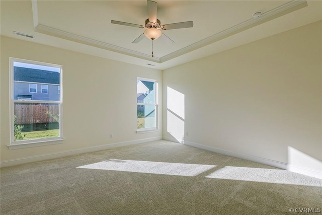 carpeted spare room featuring crown molding, a tray ceiling, and ceiling fan