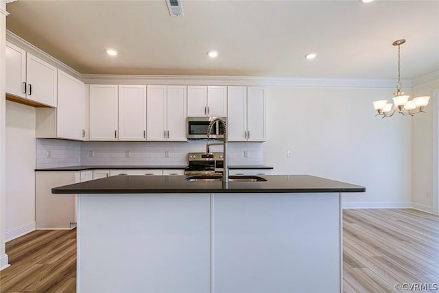 kitchen featuring white cabinetry, appliances with stainless steel finishes, and an island with sink