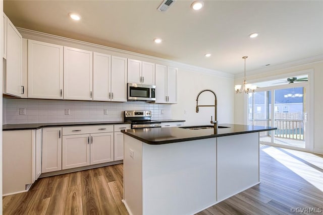 kitchen with hanging light fixtures, an island with sink, white cabinets, and appliances with stainless steel finishes