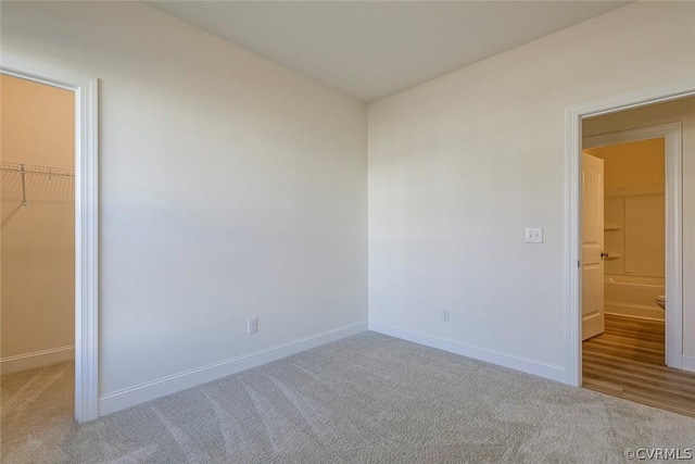 unfurnished bedroom with light carpet, a spacious closet, and a closet