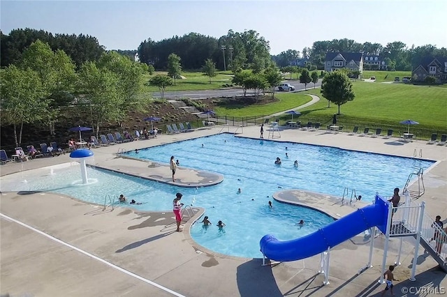 view of swimming pool with a yard, a water slide, and a patio area