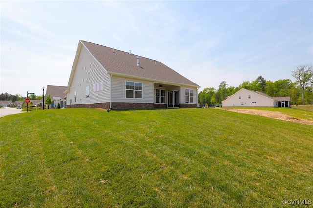 rear view of property with ceiling fan and a yard