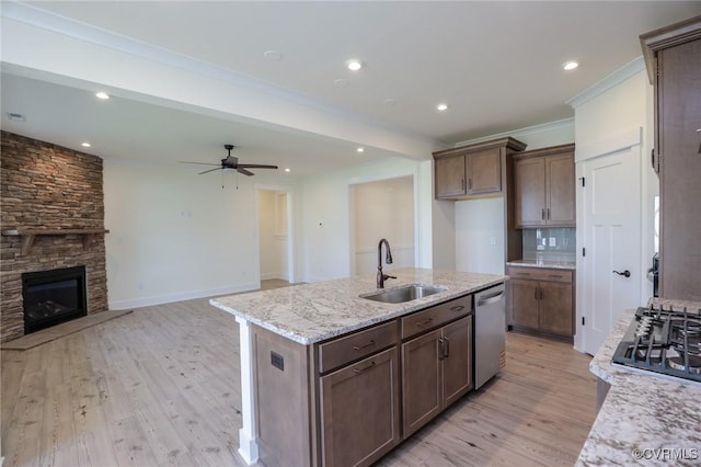 kitchen featuring a sink, stainless steel appliances, a ceiling fan, light wood-type flooring, and light stone counters