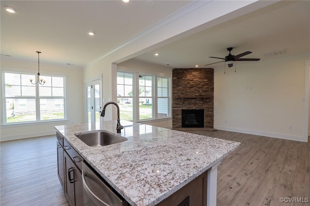 kitchen featuring a sink, stainless steel dishwasher, light wood-style flooring, baseboards, and ornamental molding