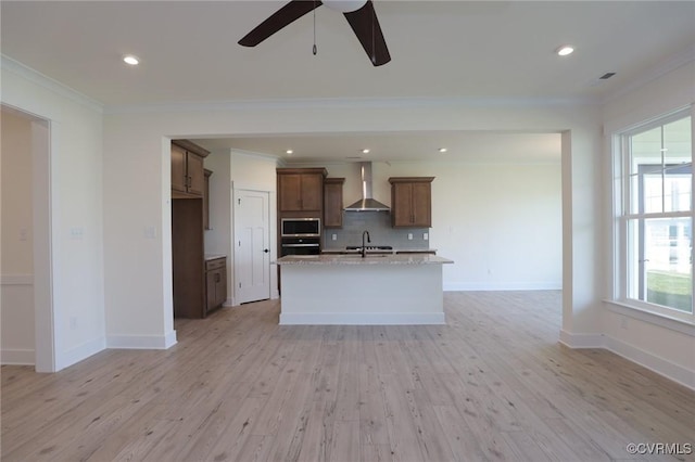 kitchen with stainless steel microwave, wall chimney exhaust hood, crown molding, wall oven, and a ceiling fan