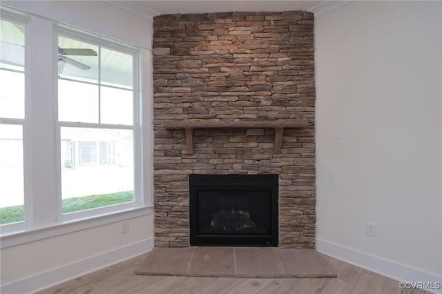 detailed view of baseboards, a fireplace, and wood finished floors