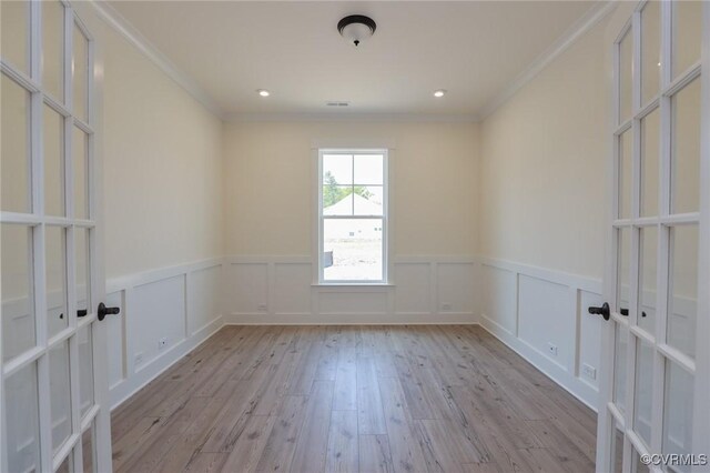 empty room with ornamental molding, wood finished floors, wainscoting, french doors, and recessed lighting