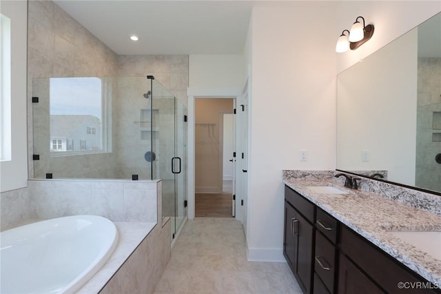 bathroom featuring a stall shower, a bath, double vanity, and a spacious closet