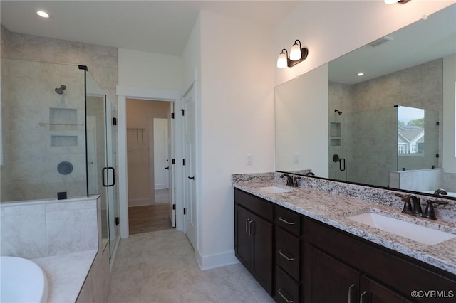 full bathroom featuring a shower stall, a spacious closet, double vanity, a bath, and recessed lighting