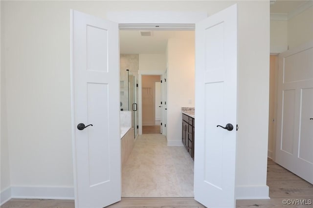 bathroom with a stall shower, vanity, and baseboards
