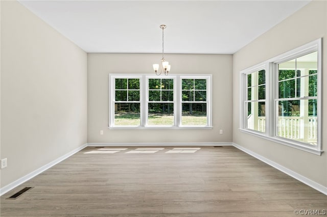 unfurnished dining area with a notable chandelier and light hardwood / wood-style floors