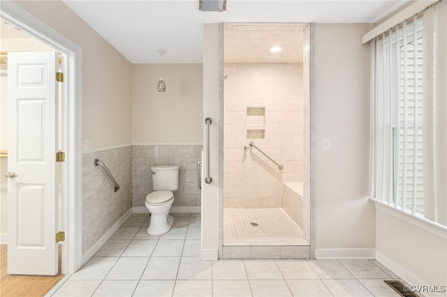 bathroom with tile patterned floors, toilet, and tiled shower