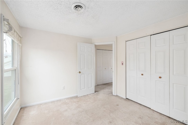 unfurnished bedroom with light colored carpet and a textured ceiling