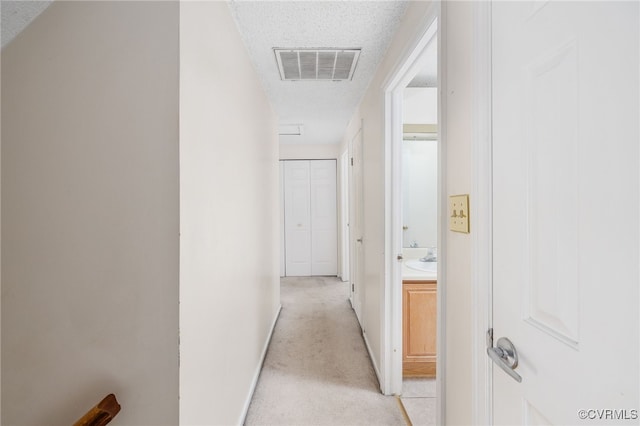 corridor featuring light carpet and a textured ceiling