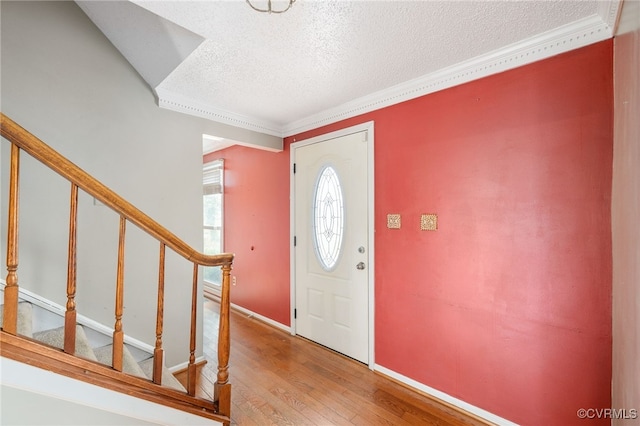 entryway featuring wood-type flooring, a textured ceiling, and ornamental molding