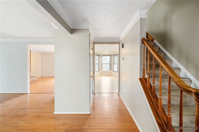 hallway featuring light hardwood / wood-style flooring, a textured ceiling, and ornamental molding