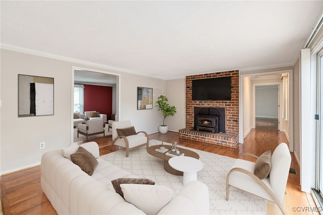 living room featuring a wood stove, light hardwood / wood-style flooring, and ornamental molding