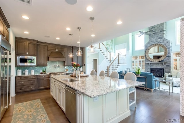 kitchen featuring ceiling fan, sink, pendant lighting, a kitchen bar, and appliances with stainless steel finishes