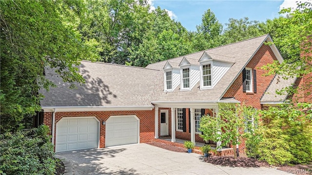 cape cod home with covered porch and a garage