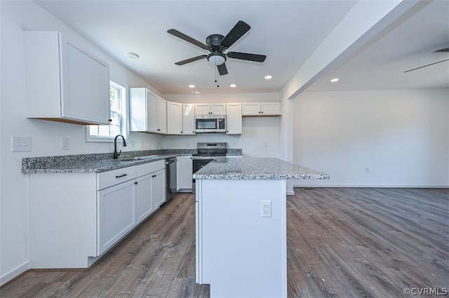 kitchen with white cabinetry, sink, a center island, light stone countertops, and appliances with stainless steel finishes