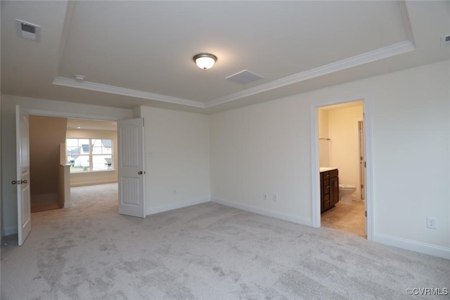 spare room with ornamental molding, light carpet, and a tray ceiling