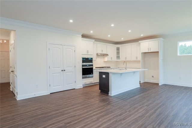 kitchen featuring white cabinetry, sink, dark hardwood / wood-style floors, crown molding, and an island with sink