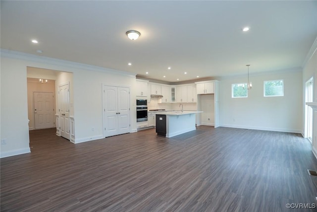 kitchen with dark wood-type flooring, white cabinets, sink, hanging light fixtures, and a kitchen island