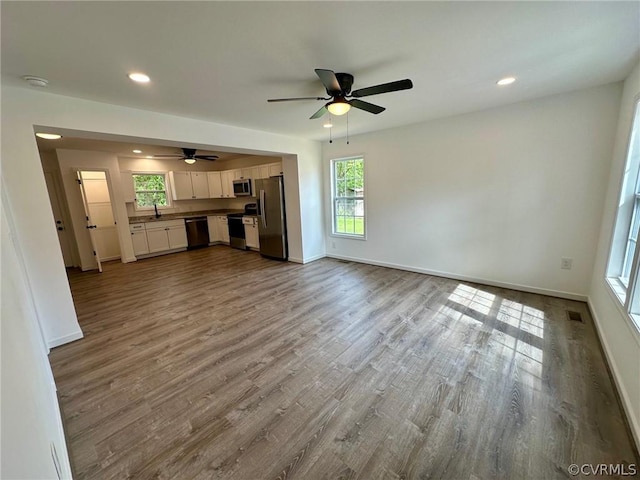 unfurnished living room with ceiling fan, sink, and light hardwood / wood-style flooring