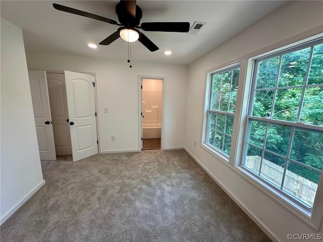 unfurnished bedroom featuring ceiling fan, ensuite bathroom, and light carpet