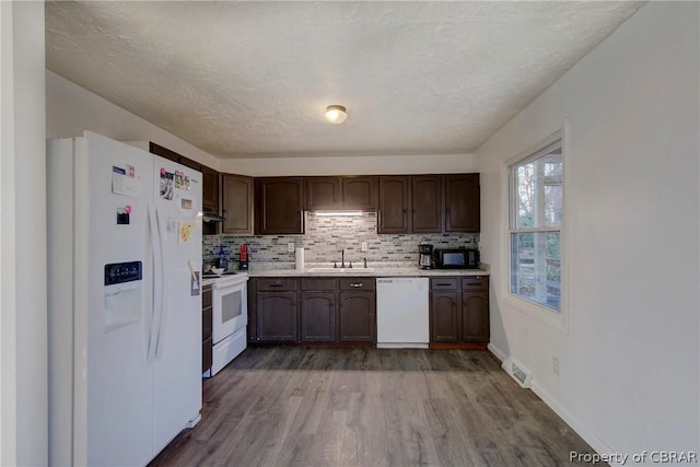 kitchen with dark brown cabinetry, sink, hardwood / wood-style floors, and white appliances