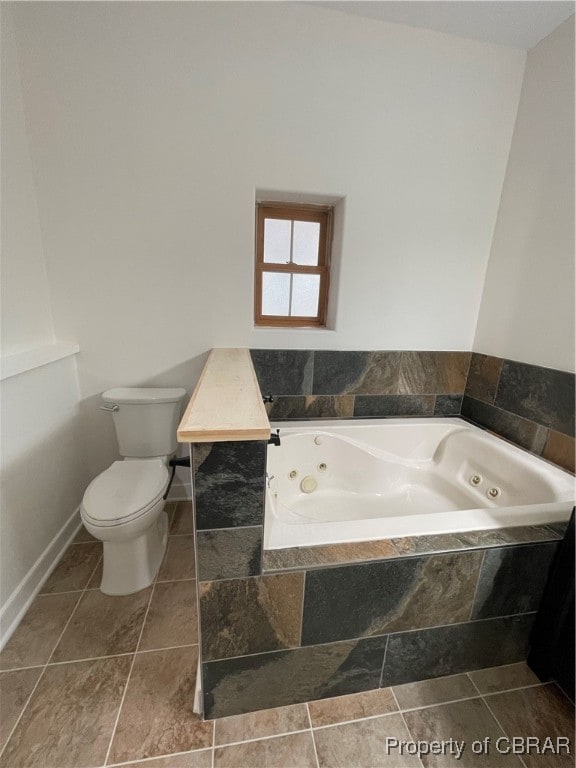 bathroom with tile patterned flooring, a relaxing tiled tub, and toilet