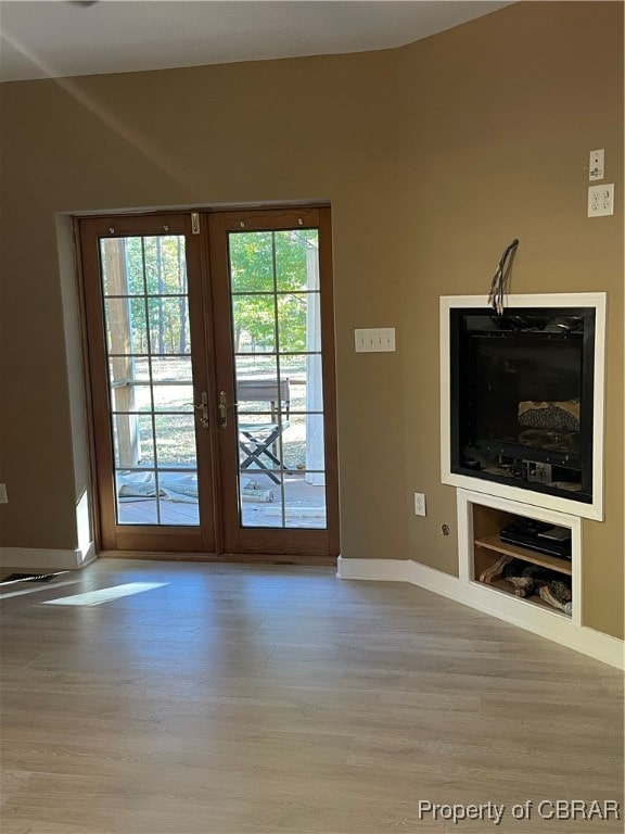 unfurnished living room with french doors, light wood-type flooring, and built in shelves