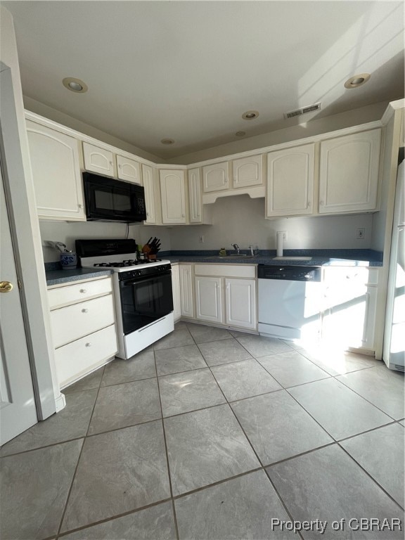 kitchen with white cabinetry, white appliances, and light tile patterned floors