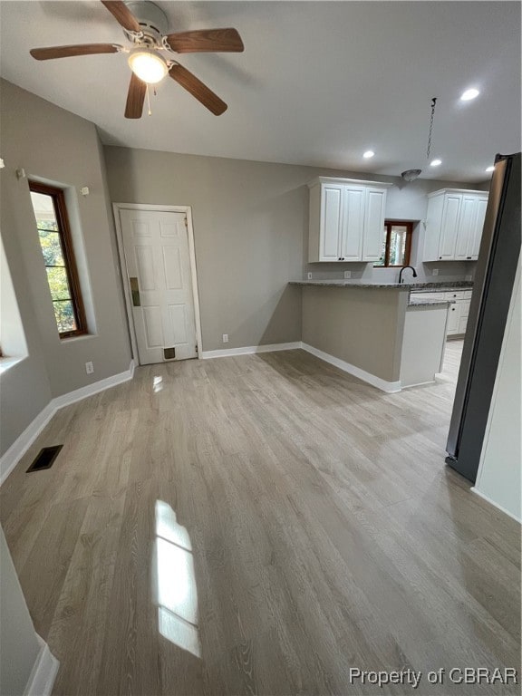 unfurnished living room with ceiling fan and light wood-type flooring