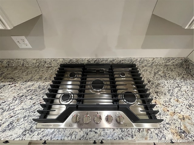 room details featuring light stone countertops, white cabinetry, and stainless steel gas cooktop