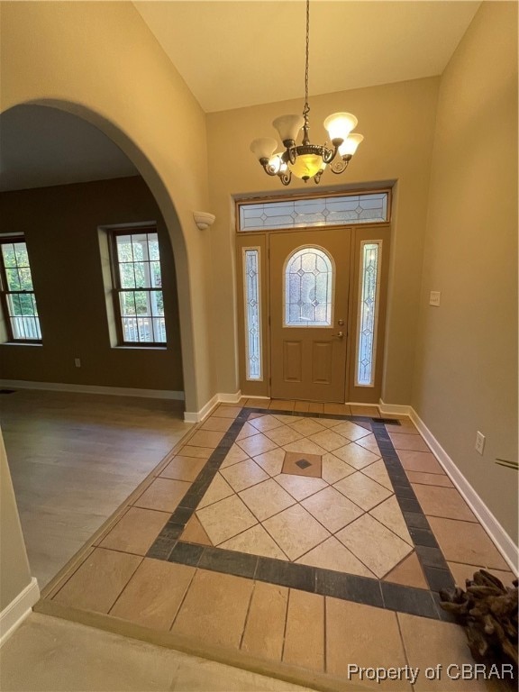 entrance foyer with a chandelier, a healthy amount of sunlight, and wood-type flooring