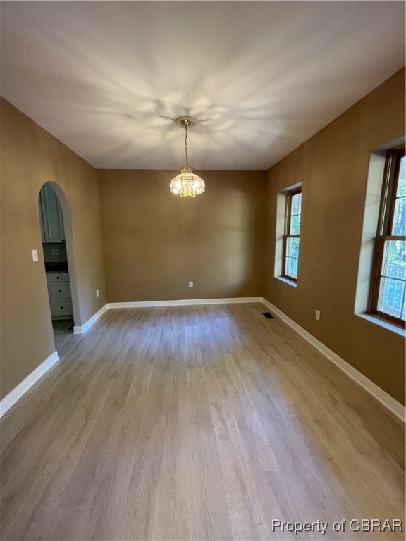 unfurnished room featuring a chandelier and light hardwood / wood-style flooring