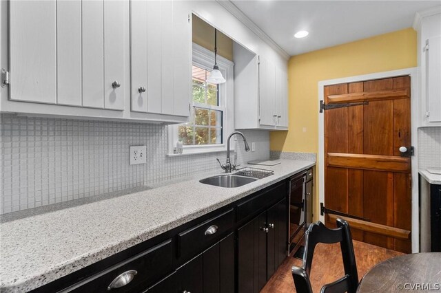 kitchen featuring sink, pendant lighting, light stone counters, backsplash, and white cabinetry