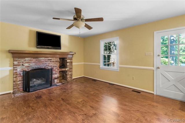 unfurnished living room featuring wood-type flooring, a brick fireplace, and ceiling fan