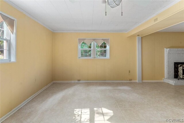 unfurnished living room with light tile patterned flooring, crown molding, and a brick fireplace