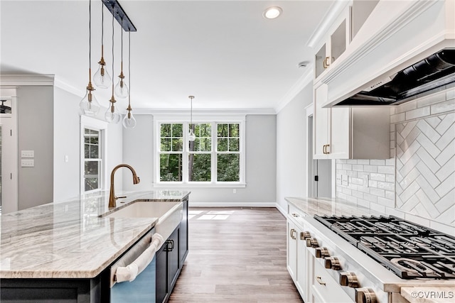 kitchen featuring custom range hood, hanging light fixtures, white cabinets, stainless steel appliances, and a kitchen island with sink