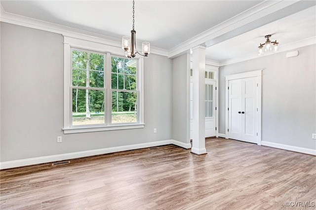 unfurnished room with wood finished floors, baseboards, decorative columns, crown molding, and a notable chandelier