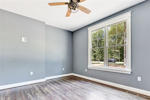 unfurnished room with ceiling fan, wood-type flooring, and a wealth of natural light