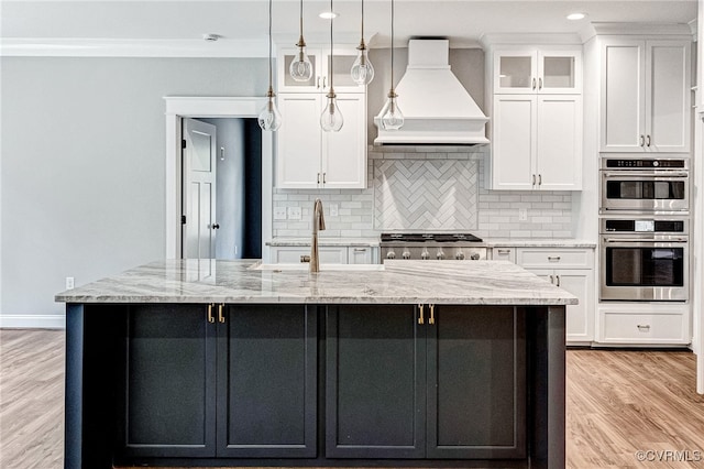 kitchen featuring light hardwood / wood-style floors, appliances with stainless steel finishes, custom range hood, and white cabinetry