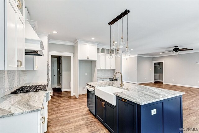 kitchen with tasteful backsplash, sink, ceiling fan with notable chandelier, white cabinets, and light hardwood / wood-style flooring