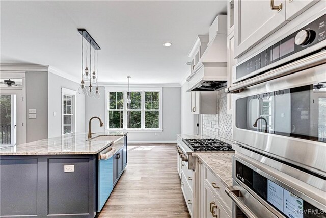 kitchen with an island with sink, white cabinets, an inviting chandelier, backsplash, and decorative light fixtures