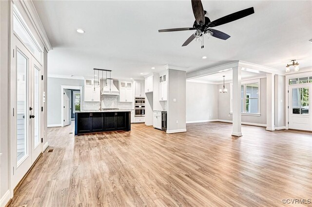 unfurnished living room featuring light wood-type flooring, ceiling fan, and crown molding