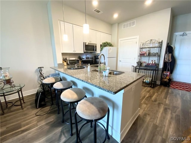 kitchen with a sink, visible vents, white cabinetry, appliances with stainless steel finishes, and dark wood finished floors